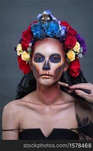 Closeup portrait of a woman with a sugar skull makeup dressed with flower crown. Halloween concept