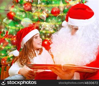 Closeup portrait of adorable baby girl with Santa Claus sitting near beautiful Christmas tree background and reading magical winter fairytale, happy childhood concept