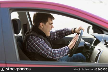 Closeup portrait of aggressive male driver honking in traffic jam