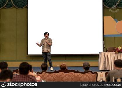 Closeup portrait of asian Speaker with casual suit on the stage over the presentation screen in the conference hall or seminar meeting, business and education concept