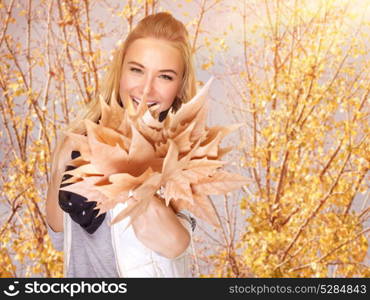 Closeup portrait of attractive blond female having fun in autumn park, holding in hand beautiful bouquet of dry maple foliage