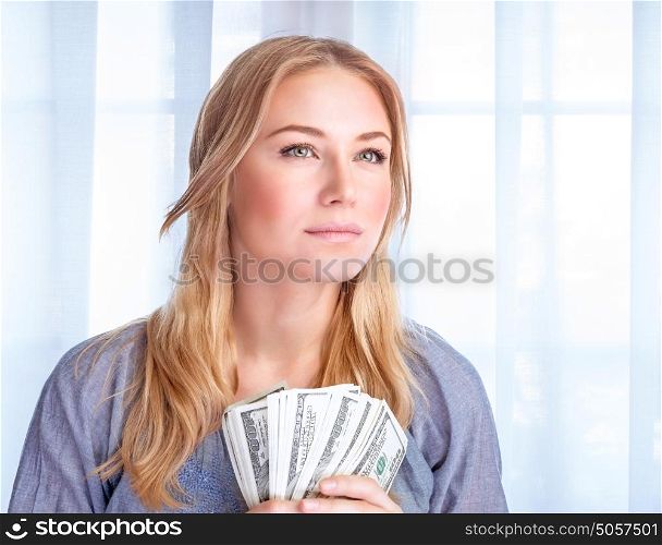 Closeup portrait of attractive serious young business woman holding in hands american dollars, winning financial lottery, success concept