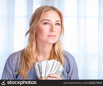 Closeup portrait of attractive serious young business woman holding in hands american dollars, winning financial lottery, success concept