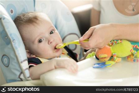 Closeup portrait of baby boy eating puree from spoon