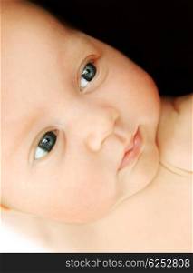 Closeup portrait of beautiful baby face over black background