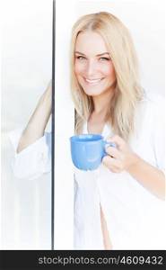 Closeup portrait of beautiful blond woman drinking tea at home near window, morning beverage, peace and happiness concept&#xA;