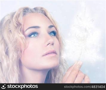 Closeup portrait of beautiful blond woman holding in hand magical glowing snowflakes, with wonder looking on Christmas miracle