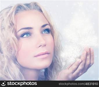 Closeup portrait of beautiful blond woman holding in hand magical glowing snowflakes, gorgeous snow queen, Christmas miracle