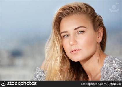 Closeup portrait of beautiful blond woman outdoors over soft focus background, healthy natural beauty