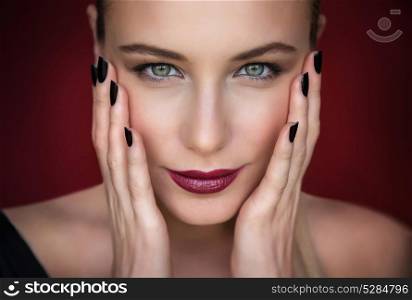 Closeup portrait of beautiful fashion model over dark red background, pretty woman with stylish makeup, beauty salon