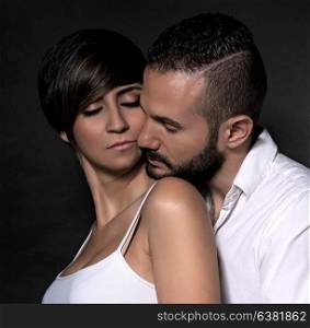 Closeup portrait of beautiful gentle couple in love, hugging with closed eyes of pleasure isolated on black background, romantic relationship