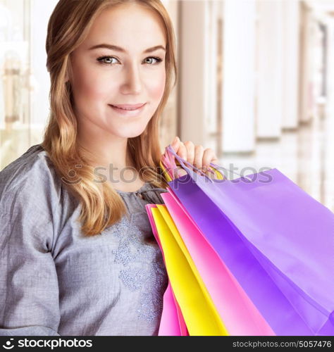 Closeup portrait of beautiful happy woman doing purchase in shopping center, carrying colorful paper bags, spending money concept