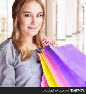 Closeup portrait of beautiful happy woman doing purchase in shopping center, carrying colorful paper bags, spending money concept