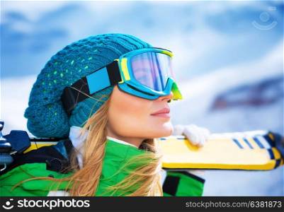 Closeup portrait of beautiful skier girl wearing mask and holding ski, enjoying winter holidays
