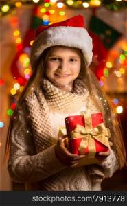 Closeup portrait of beautiful smiling girl holding gift box at Christmas eve