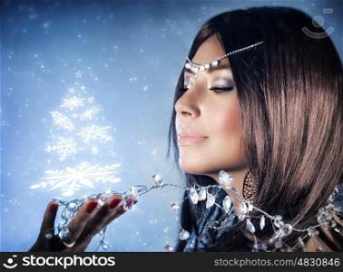 Closeup portrait of beautiful snow queen with crown on head holding on hand magical glowing Christmas tree, winter fashion and makeup