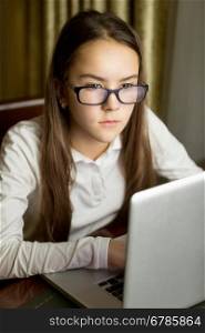 Closeup portrait of beautiful teen girl in eyeglasses using laptop