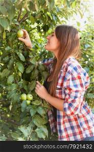 Closeup portrait of beautiful woman picking green apple from tree