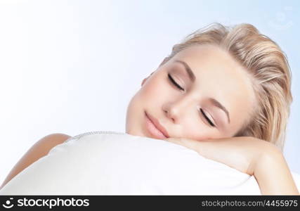 Closeup portrait of beautiful woman sleeping on the pillow isolated on blue and white background, happy calm day dreaming, conception of relaxation