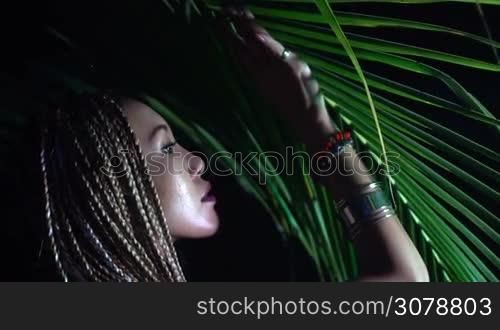 Closeup portrait of beautiful woman with braids posing near the palm tree in the jungle - video in slow motion