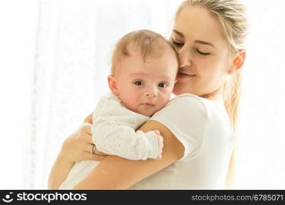 Closeup portrait of beautiful young mother cuddling her adorable 3 months old baby boy
