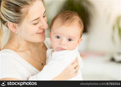 Closeup portrait of beautiful young mother holding her baby on hands
