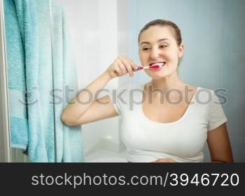 Closeup portrait of beautiful young woman brushing teeth at bathroom