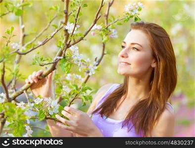 Closeup portrait of beautiful young woman enjoying nature in blooming garden, spring time season, relaxation outdoors