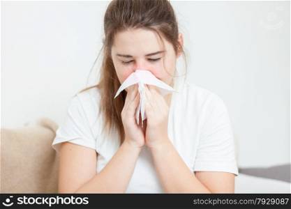 Closeup portrait of brunette woman sneezing in paper tissue