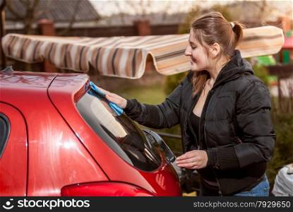 Closeup portrait of brunette woman washing red car outdoor