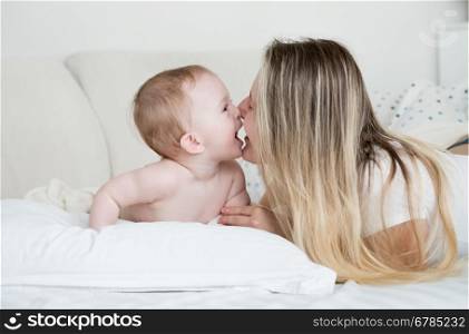 Closeup portrait of cheerful baby with mother lying on big white pillow