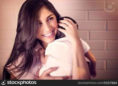 Closeup portrait of cheerful smiling mother with sleeping newborn daughter on her shoulder at home, happy young loving family, new life concept