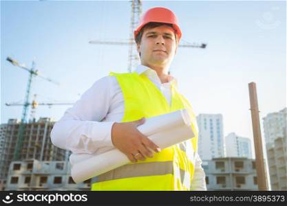 Closeup portrait of construction manager posing with blueprints