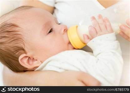 Closeup portrait of cute 3 months old baby boy drinking milk from bottle