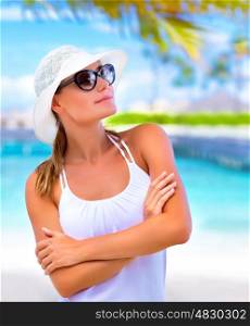 Closeup portrait of cute blond girl enjoying summer day on the beach, wearing white hat and stylish sunglasses, vacation concept