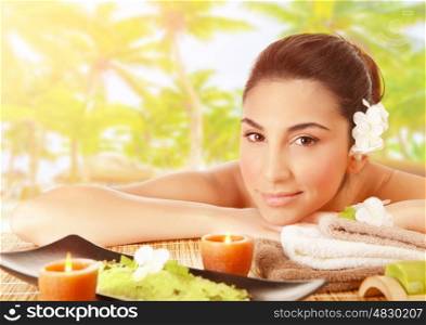 Closeup portrait of cute brunet girl lying down on massage table outdoors, tropical beach, luxury spa resort, alternative therapy, summer relaxation concept