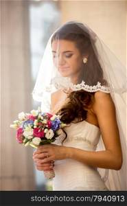 Closeup portrait of cute brunette bride with wedding bouquet at sunny day