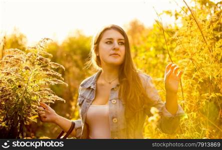 Closeup portrait of cute brunette woman walking at meadow filled with sunlight