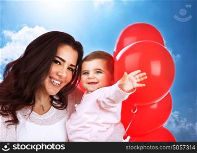 Closeup portrait of cute cheerful mother carry sweet baby daughter, having fun outdoors, playing with red balloons, happy family portrait