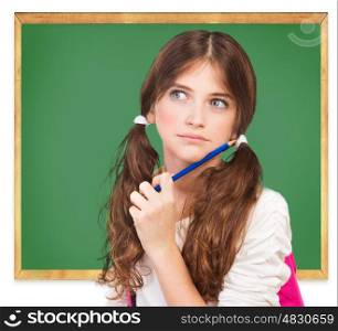 Closeup portrait of cute girl standing near chalkboard and try to remember answer on question, passing exam, back to school concept