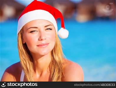 Closeup portrait of cute girl wearing red Santa hat enjoying luxury beach resort, travel to Maldives on Christmas time holidays