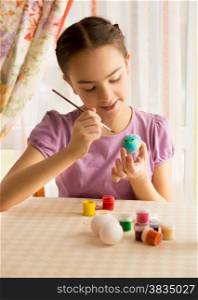 Closeup portrait of cute girl with brush painting Easter eggs