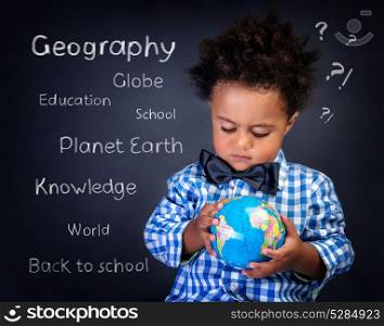 Closeup portrait of cute little African boy with small globe in hands, preparing to geography lesson, back to school concept