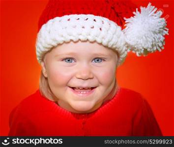 Closeup portrait of cute little baby girl wearing Santa hat isolated on red background, funny festive costume for Christmas celebration