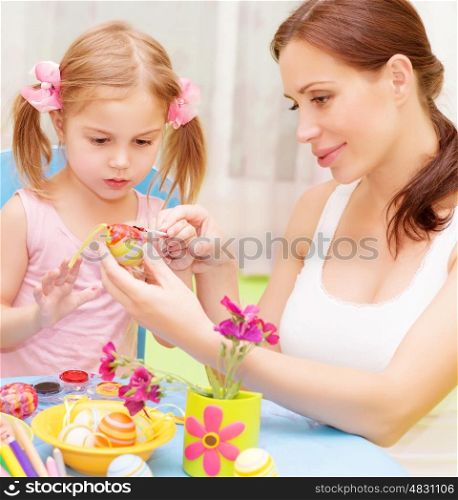 Closeup portrait of cute little baby girl with beautiful young mother paint Easter eggs, traditional Christian symbol&#xA;