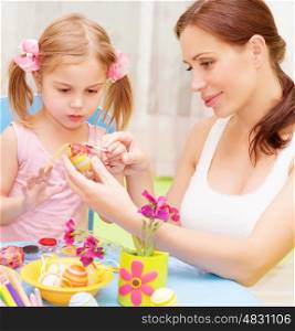 Closeup portrait of cute little baby girl with beautiful young mother paint Easter eggs, traditional Christian symbol&#xA;