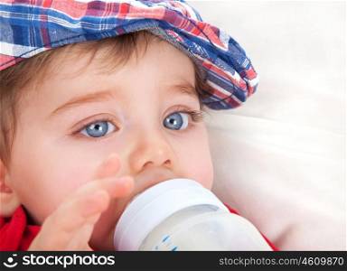 Closeup portrait of cute little boy with big blue eyes eating, drinking milk from bottle, healthy nutrition for kids, tasty baby food