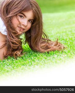 Closeup portrait of cute little girl lying down fresh green grass field, having fun outdoor on backyard, happy childhood concept, white copy space