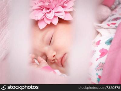 Closeup portrait of cute little kid sleeping at home, baby girl wearing nice pajama and pink decorative flower on head, happy peaceful childhood