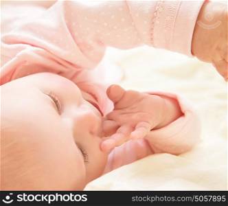 Closeup portrait of cute little newborn baby wearing pink clothes and sleep at home, day dreaming, innocence and tenderness concept